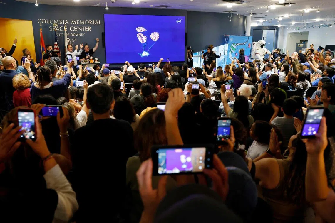 People celebrate as they watch a live broadcast of the Artemis II splashdown during a watch party at the Columbia Memorial Space Center in Downey, California.