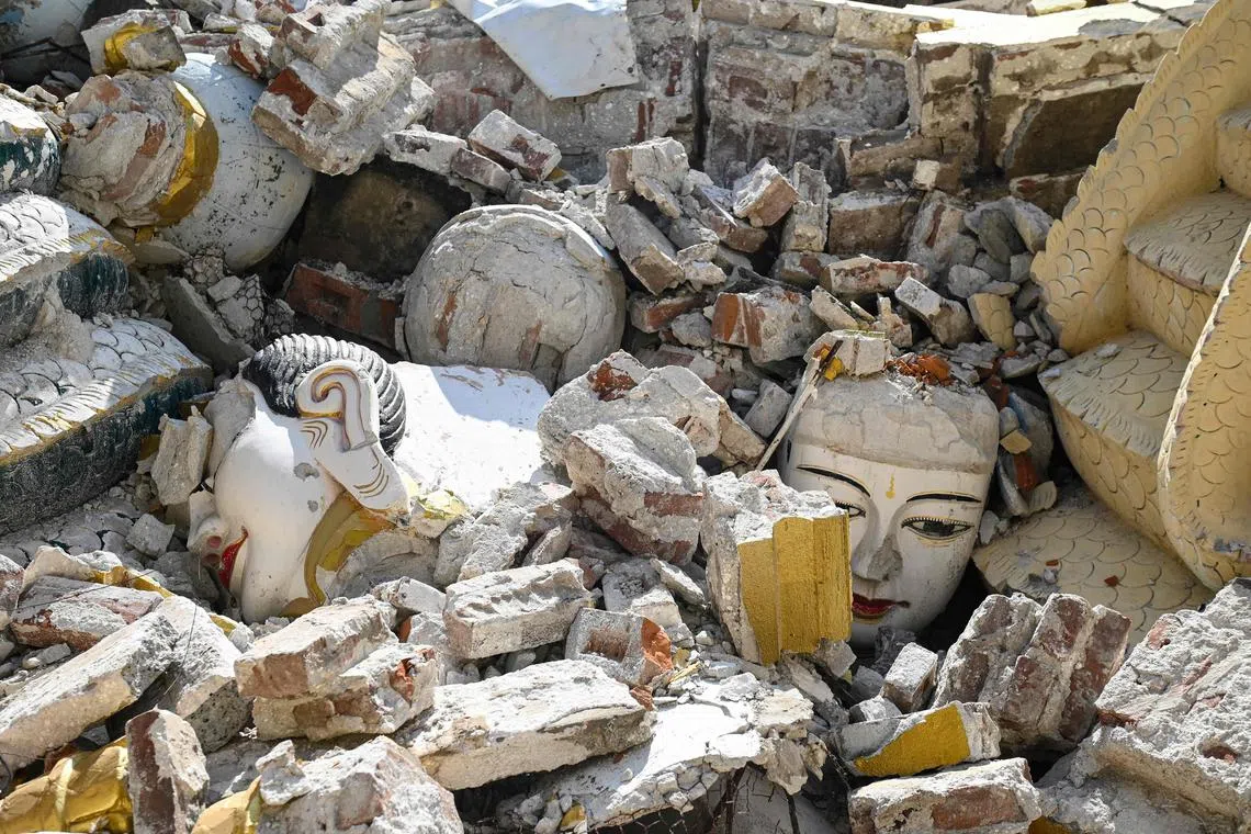 TOPSHOT - This photo taken on April 12, 2025 shows damaged Buddha statues surrounded by the debris of a collapsed building in Mandalay, following the devastating March 28 earthquake. When a massive earthquake hit Myanmar last month, centuries of sacred history tumbled down -- towering Buddha idols, sky-scraping stupas and the pure-white pagoda where 83-year-old Khin Sein has prayed for most of her life. (Photo by Sai Aung MAIN / AFP) / To go with 'MYANMAR-THAILAND-EARTHQUAKE-HISTORY-HERITAGE,REPORTAGE' by Lynn MYAT