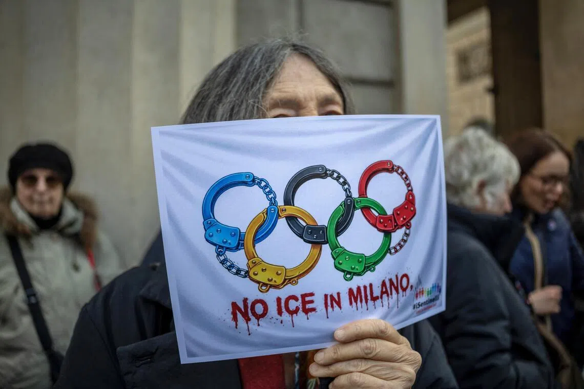 An anti-ICE protester in Milan on Jan 31 holding a sign depicting the Olympic rings as handcuffs.