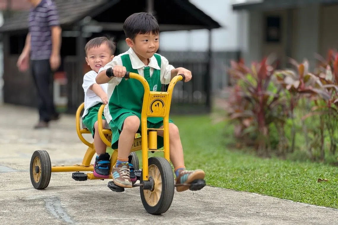 Elio Low and Enzo Low (front) cycle around the compound of Kinderland Academy @ Yio Chu Kang.