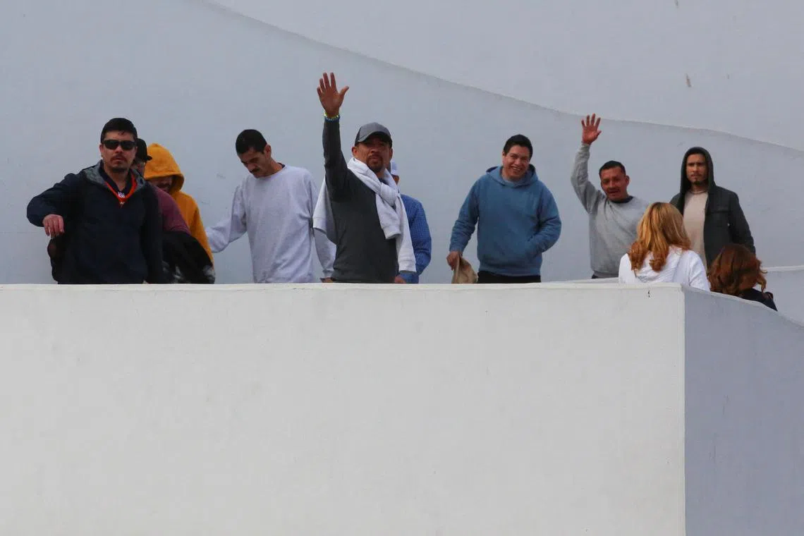 Migrants deported from the US wave while walking towards a van of the Mexican National Migration Institute, at El Chaparral border crossing, in Tijuana, Mexico  on Jan 22.