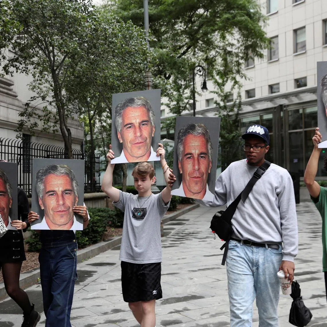 Demonstrators hold signs aloft protesting Jeffrey Epstein, as he awaits arraignment in the Southern District of New York on charges of sex trafficking of minors and conspiracy to commit sex trafficking of minors, in New York, U.S., July 8, 2019. REUTERS/Shannon Stapleton