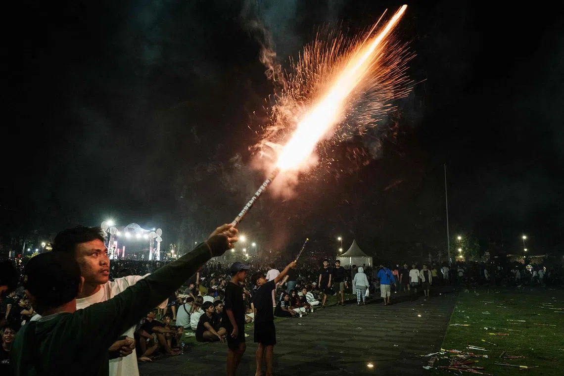Revellers let off fireworks as they celebrate the New Year in Alun-Alun Kota Gianyar in Bali, on Dec 31, 2025. 