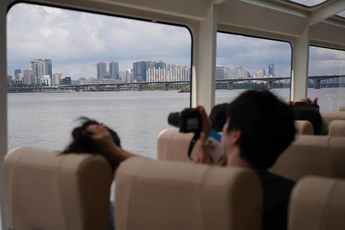 A passenger takes out a camera to take Seoul's cityscape ouside the window of Hangang Bus.