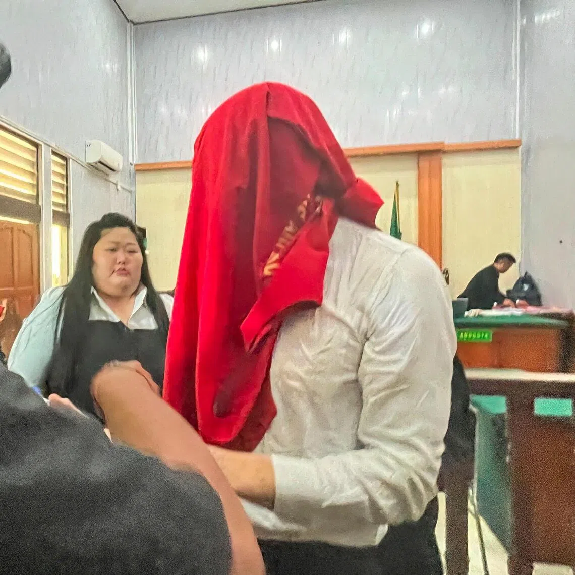 Photo of 26-year-old Swiss national Luzian Andrin Zgraggen, his face covered by a red cloth, being escorted from a courtroom in Denpasar, Bali on Aug 20.