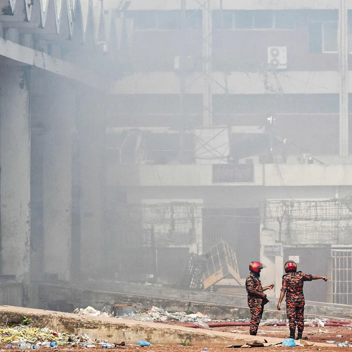 Firefighters inspect as smoke engulfs the fire-damaged cargo terminal of Hazrat Shahjalal International Airport in Dhaka on Oct 19, 2025.