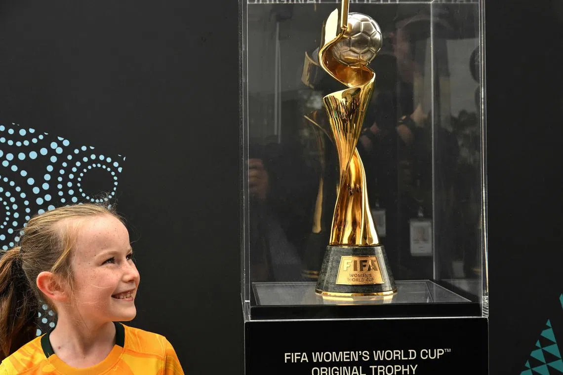 A girl smiles as she looks at the trophy for the Australia and New Zealand 2023 Women's World Cup football tournament during a tour at Taronga Zoo in Sydney on June 8, 2023. (Photo by SAEED KHAN / AFP) / -- IMAGE RESTRICTED TO EDITORIAL USE - STRICTLY NO COMMERCIAL USE --