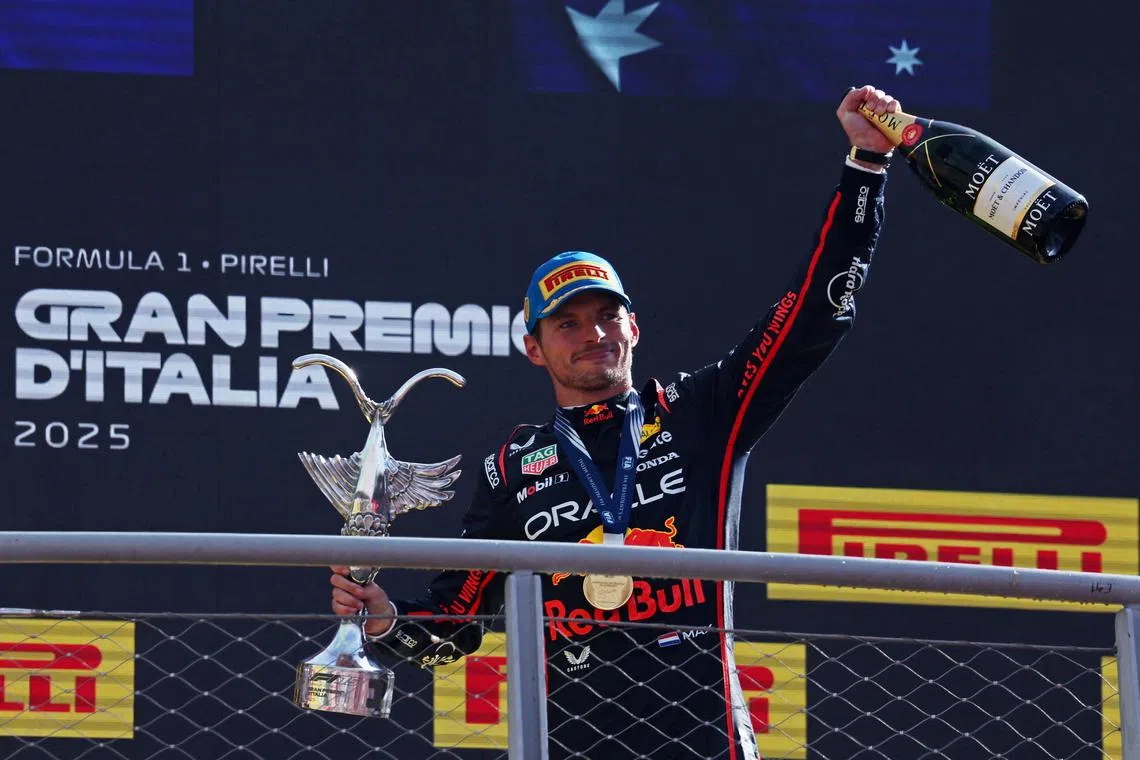 Red Bull's Max Verstappen celebrates with a trophy and champagne on the podium after winning the Italian Grand Prix.