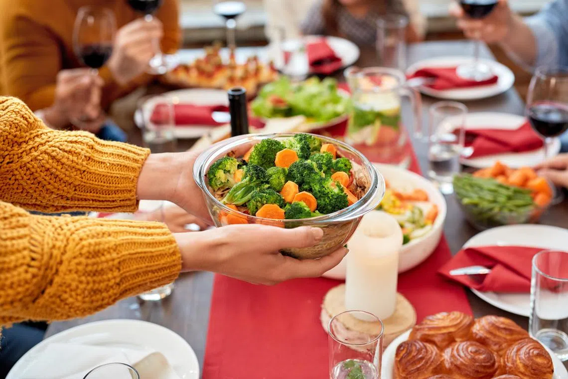 akfestive13-ol - Cropped view of woman holding bowl full vegetables over served dinner table with tasty homemade food and preparing for celebrating holidays and birthday with family