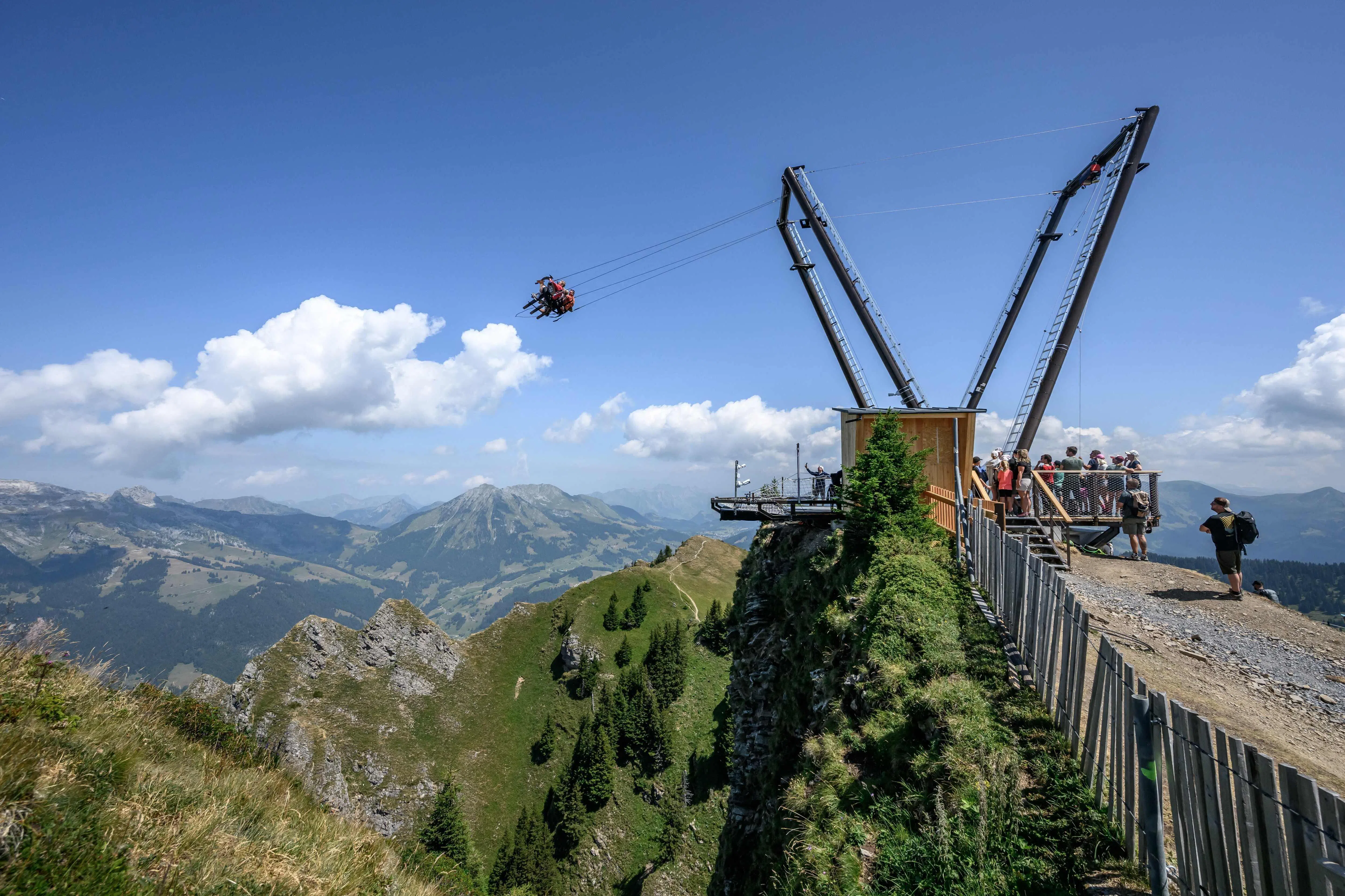 TOPSHOT - This photograph shows tourists enjoying the new BalancAIR, a giant swing at the top of the Grand Chamossaire peak, above Villars-sur-Ollon, western Switzerland, on July 20, 2026. Inaugurated at the beginning of the month, the Grand Chamossaire swing is the latest initiative by Alpine resorts to attract visitors in summer and make their ski lifts profitable, as snowfall is becoming increasingly unreliable due to climate change. (Photo by Fabrice COFFRINI / AFP)