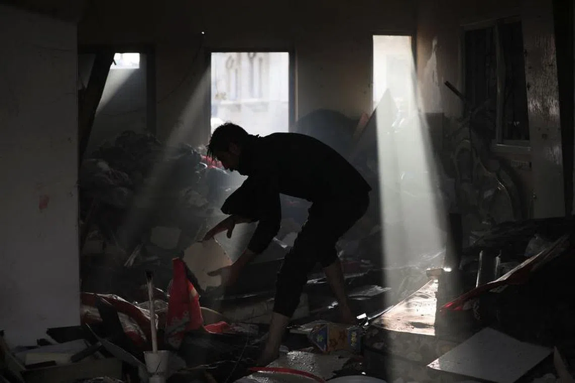 Palestinian picks up debris on the site of an Israeli strike at Maghazi refugee camp in the central Gaza Strip, amid the ongoing conflict between Israel and the Palestinian Islamist group Hamas,  January 3, 2024. REUTERS/Mohammed Al-Masri