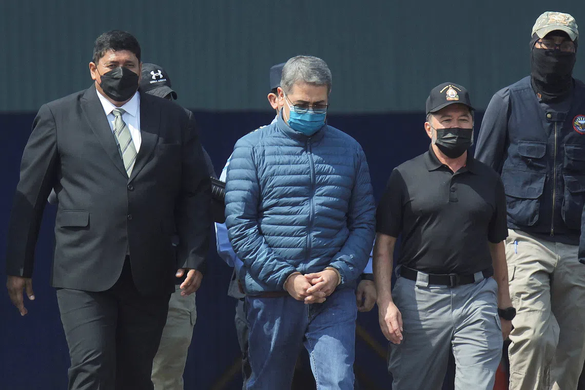 Honduras former President Juan Orlando Hernandez is escorted by authorities as he walks towards a plane of the U.S. Drug Enforcement Administration (DEA) for his extradition to the United States, to face a trial on drug trafficking and arms possession charges, at the Hernan Acosta Mejia Air Force base in Tegucigalpa, Honduras April 21, 2022. REUTERS/Fredy Rodriguez