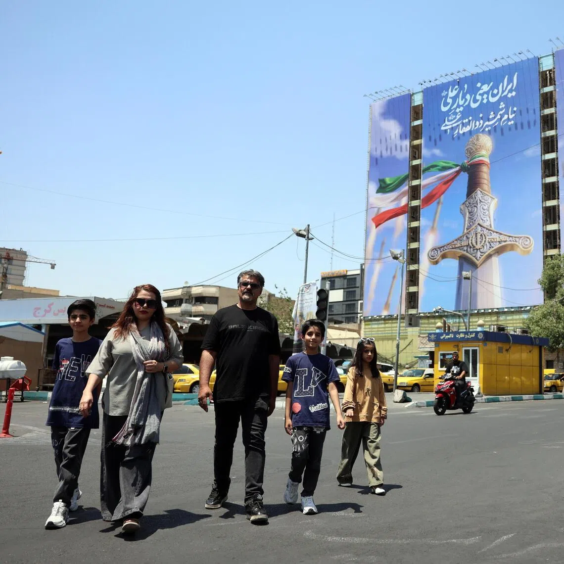 Iranians walking past a large-scale political billboard featuring Iranian missiles and a sword in Tehran, Iran, on June 11. 
