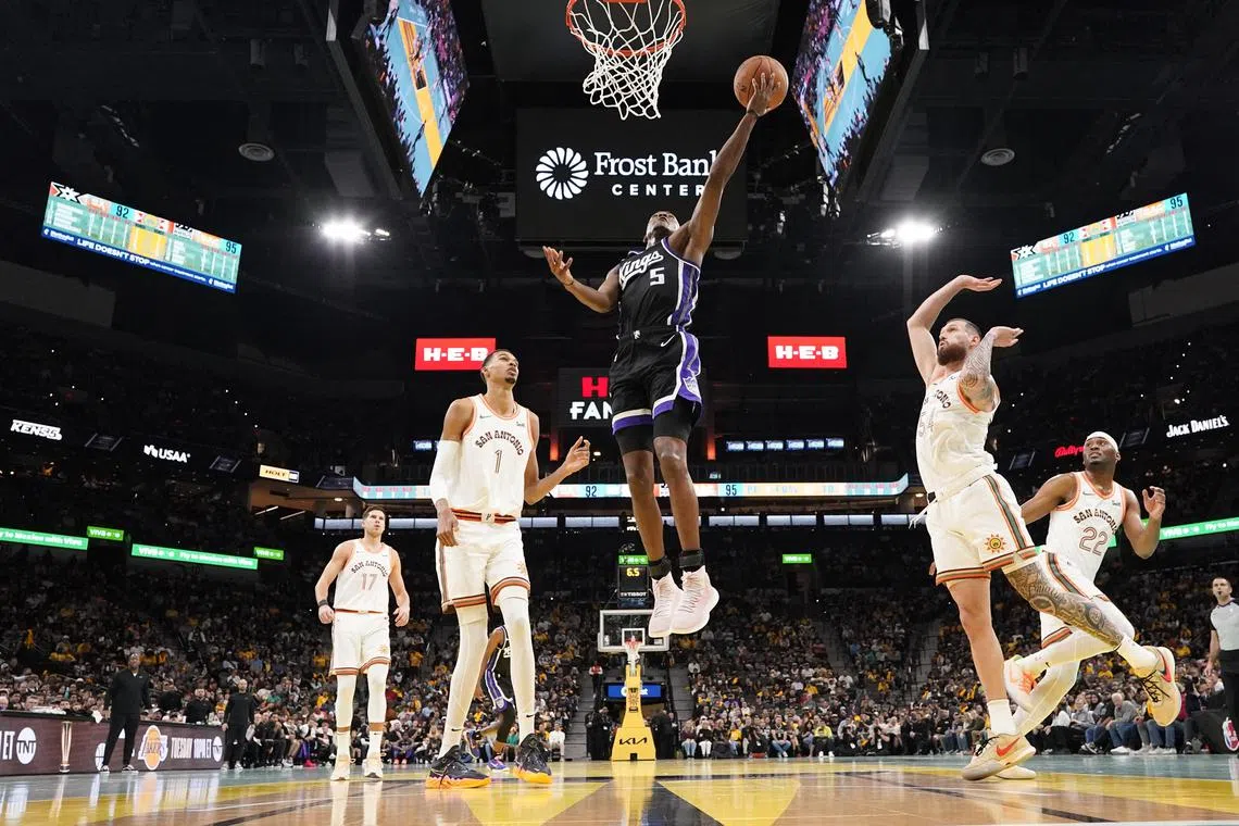 Sacramento Kings guard De'Aaron Fox drives to the basket between San Antonio Spurs forwards Victor Wembanyama and Sandro Mamukelashvili during the second half at Frost Bank Centre.