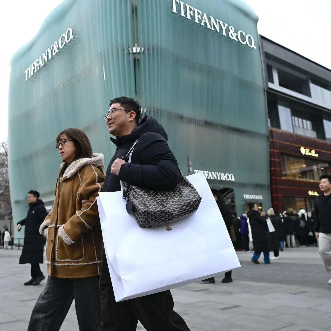 People walk out from a mall in Beijing on January 18, 2026. (Photo by WANG Zhao / AFP)