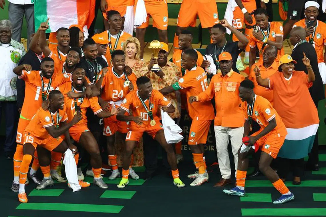 Soccer Football - Africa Cup of Nations - Final - Nigeria v Ivory Coast - Stade Olympique Alassane Ouattara, Abidjan, Ivory Coast - February 11, 2024 Ivory Coast president Alassane Ouattara with the trophy alongside the players as they celebrate after winning the Africa Cup of Nations REUTERS/Siphiwe Sibeko