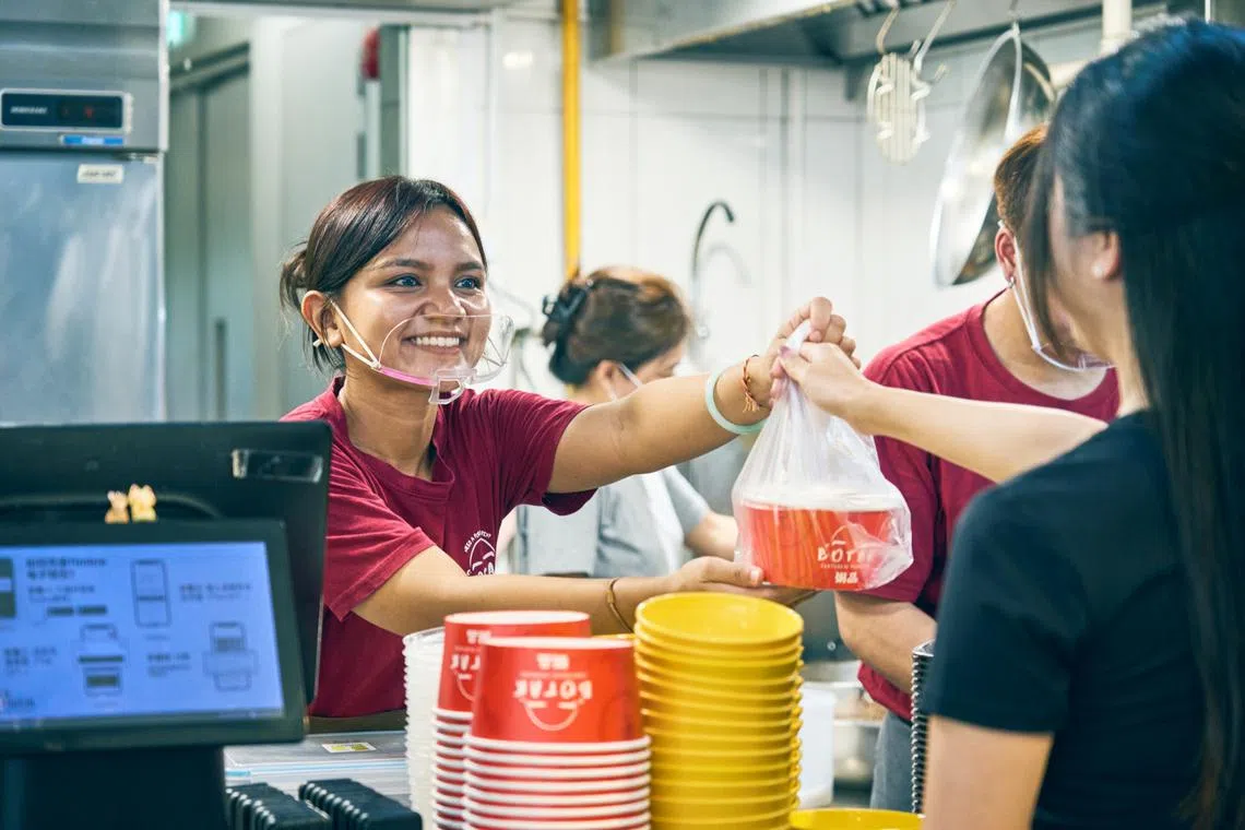 Hawker Lim Hwee Yi serving up porridge at One Punggol Hawker Centre – the first stall she built from the ground up after leaving her job as a personal security officer.