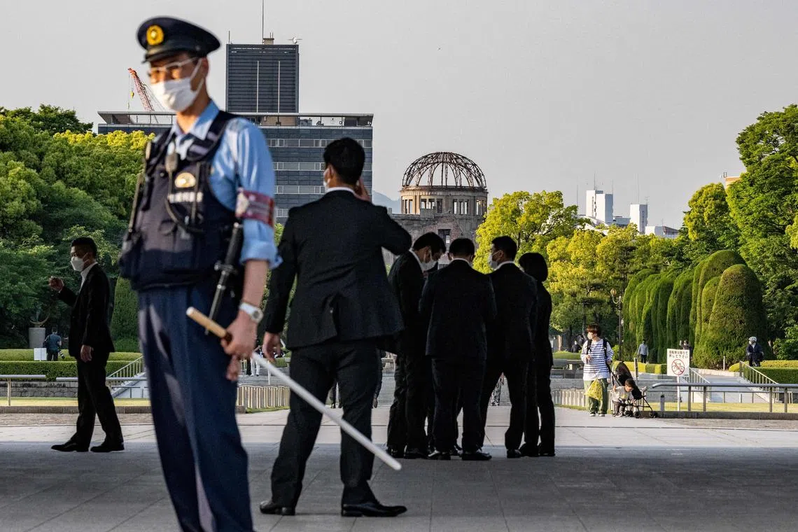 A police officer stands guard with the security personals at the Peace Memorial Park with the background of the Atomic Bomb Dome in Hiroshima, ahead of the G7 Leaders' Summit, on May 16, 2023. (Photo by Philip FONG / AFP)