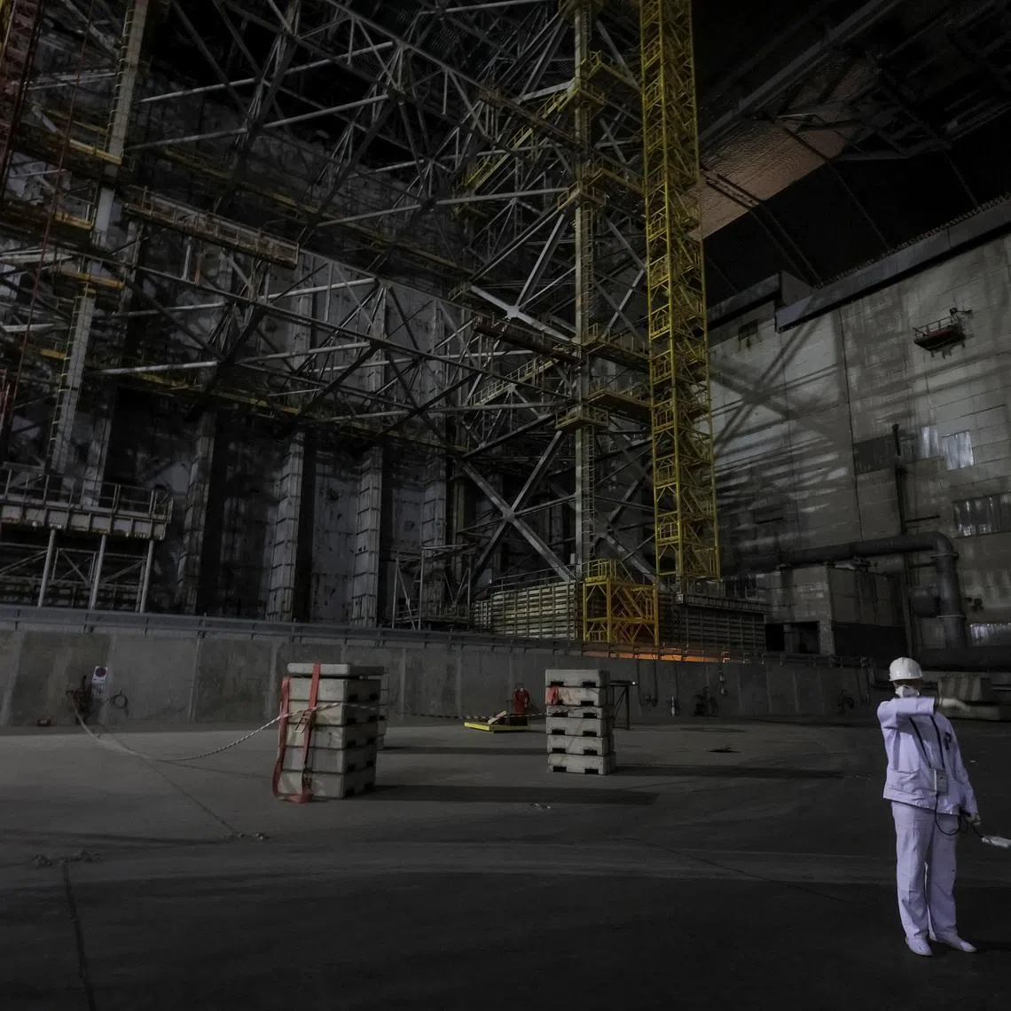 An employee measures a radiation level next to the old sarcophagus covering the damaged fourth reactor, under the New Safe Confinement (NSC) structure at the Chornobyl Nuclear Power Plant, amid Russia's attack on Ukraine, in Kyiv region, Ukraine April 22, 2026. REUTERS/Gleb Garanich