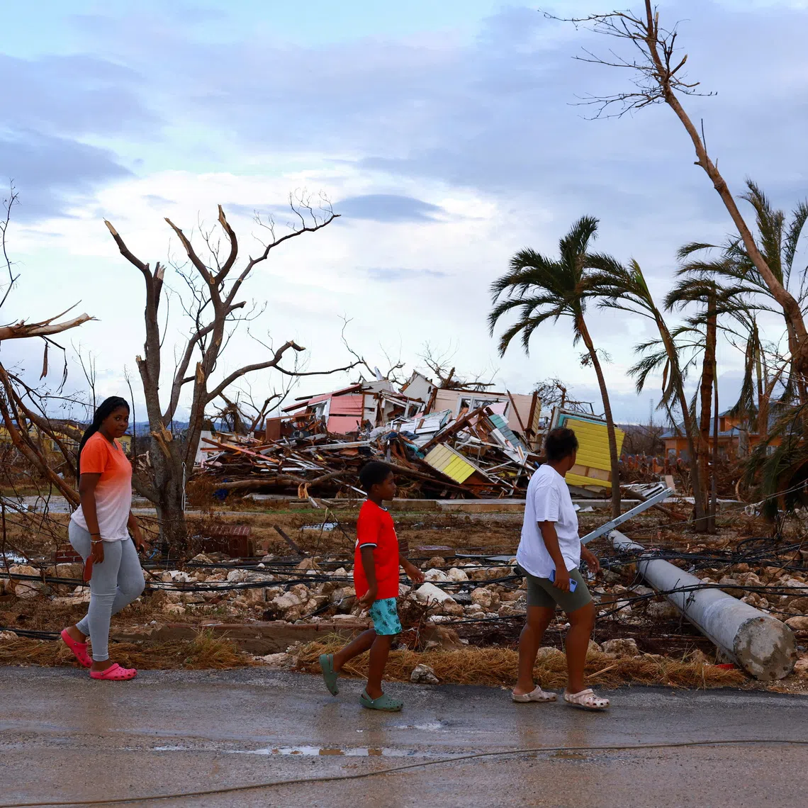 FILE PHOTO: People walk past damaged houses in the aftermath of Hurricane Melissa, in Black River, Jamaica, November 5, 2025. REUTERS/Raquel Cunha/File Photo