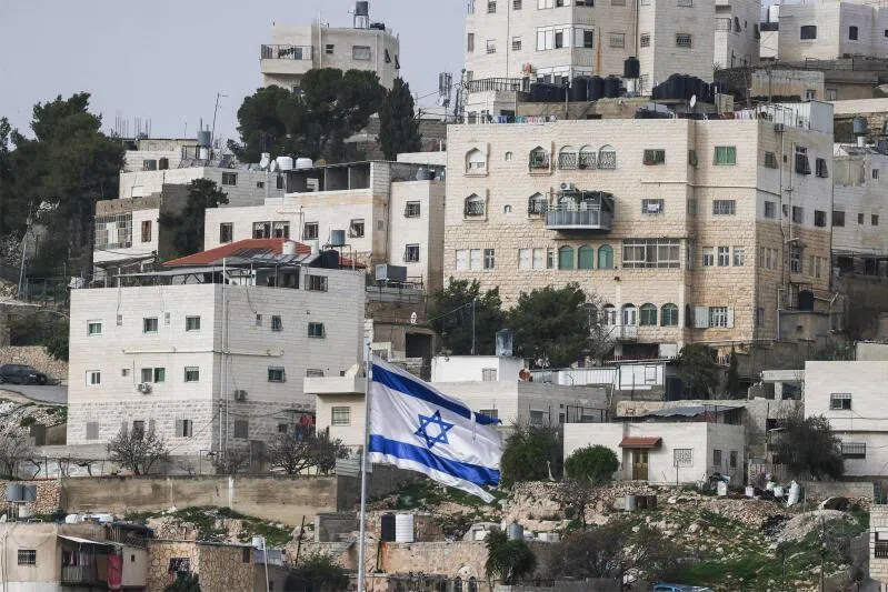 An Israeli flag fluttering above an Israeli settlement, with Palestinian buildings in the background, in the Israeli-occupied West Bank city of Hebron on Feb 9, 2026.