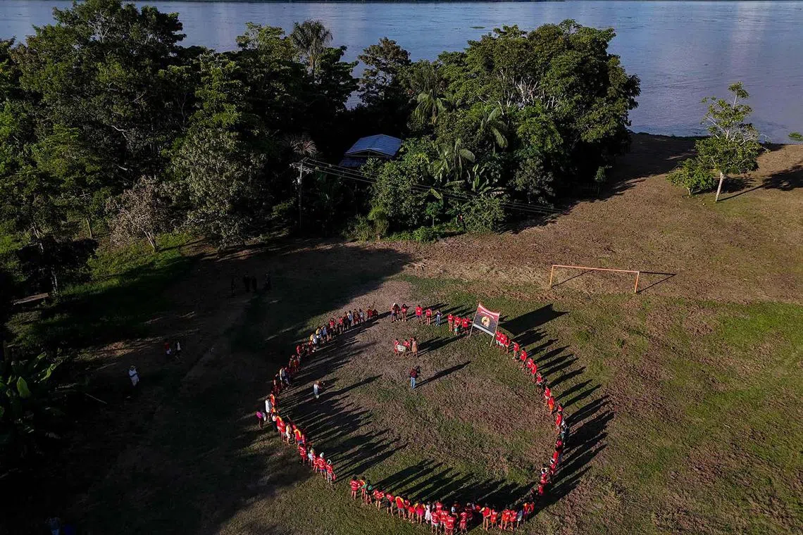 Indigenous people gathered in a circle performing a collective hug before the opening of the Alvarães Indigenous Intercultural Games and Dances, held at Marajaí Village, in Alvarães, Amazonas state, northern Brazil on April 14, 2025. 
