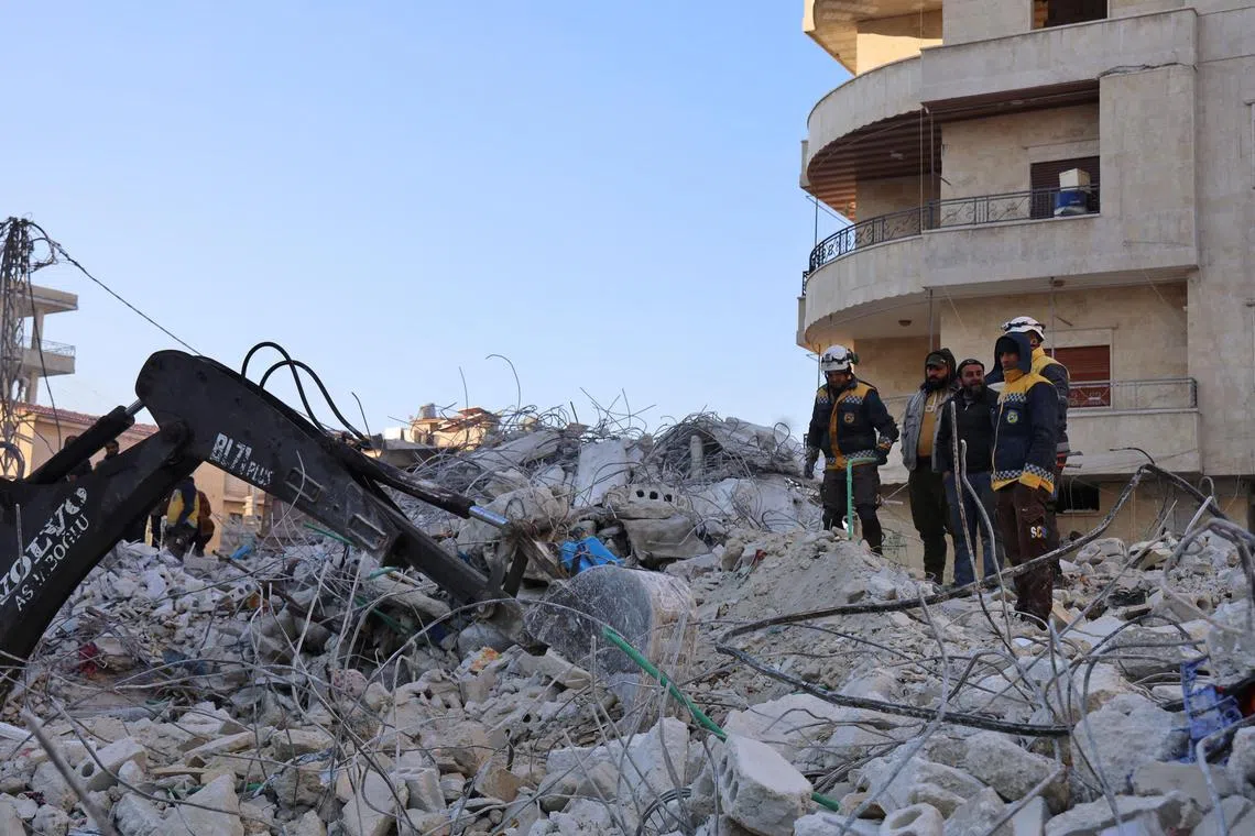 Members of the Syrian civil defence, known as the White Helmets, watch for signs of survivors in the rubble of a collapsed building, in Salqin, a village near the border with Turkey.