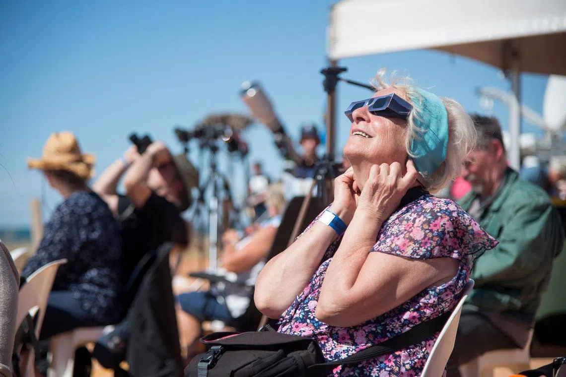 A person uses solar viewing glasses to look up at the sky ahead of a total solar eclipse at a viewing site 24km from Exmouth, Australia, April 20, 2023. 