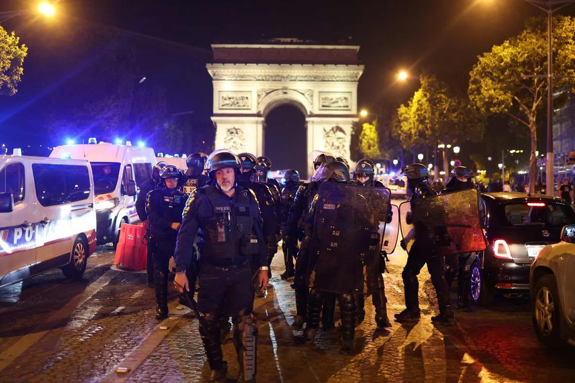 French police officers patrol in front of the Arc de Triomphe in the Champs Elysees area of Paris, on July 1, 2023.