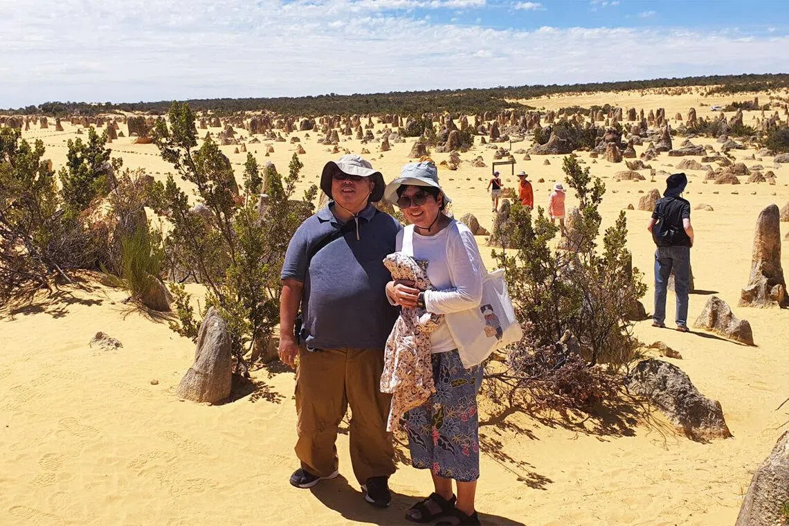 Asian Singaporean couple at Pinnacles desert, Western Australia with limestone formations in the background