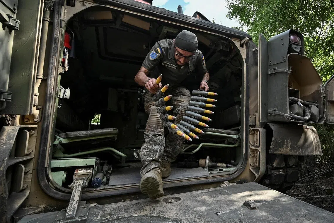 A Ukrainian soldier prepares an M2 Bradley infantry fighting vehicle for combat at a position near a front line.