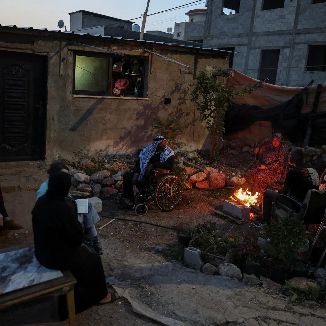 The Ghanem family sit around a fire outside a shack near Tulkarm in the Israeli‑occupied West Bank, February 16, 2026. Members of the family were displaced last year from the Tulkarm refugee camp. REUTERS/Ammar Awad  SEARCH "AWAD TULKAREM" FOR THIS STORY. SEARCH "WIDER IMAGE" FOR ALL STORIES.