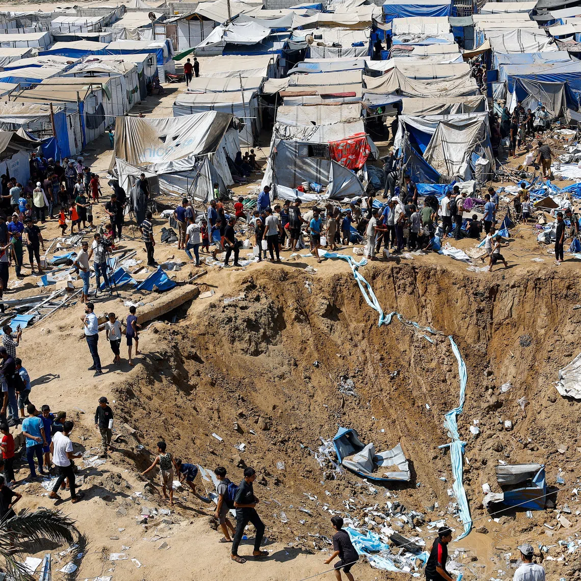 Palestinians inspect the site of an overnight Israeli strike on a medicine warehouse, next to tents sheltering displaced Palestinians, in Deir al-Balah, in the central Gaza Strip.
