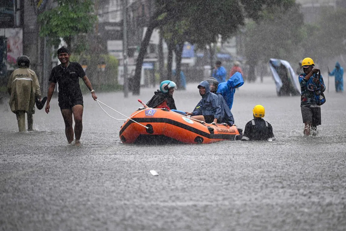 Local residents move hotel guests using a rubber boat through the water on an inundated street amid floods following heavy rain at Legian Kuta near Denpasar on Indonesia’s resort island of Bali on Feb 24. 