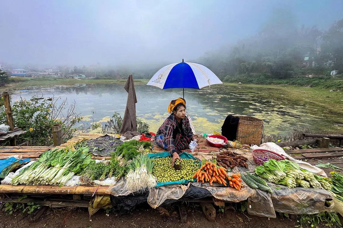 TOPSHOT - A vendor prepares her stall as she waits for customer at a street market in Taunggyi, Myanmar’s northeast Shan Sate on November 13, 2024. (Photo by Sai Aung MAIN / AFP)