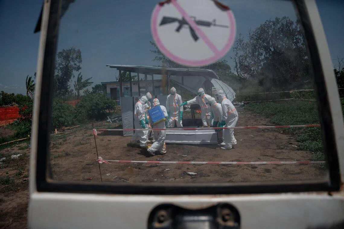 TOPSHOT - Red Cross volunteers wearing personal protective equipment gather around the casket containing the body of an Ebola virus disease victim from the morgue of the Rwampara health centre, Ituri Province, Democratic Republic of Congo, on June 8, 2026 before loading it into a vehicle for transfer to a cemetery as part of safe and dignified burial operations aimed at preventing the spread of the virus. The head of the World Health Organization visited Uganda on Monday and praised its efforts to limit the spread of an Ebola outbreak from neighbouring Democratic Republic of Congo. The WHO has declared an international health emergency over the outbreak which has caused 515 confirmed infections in the DRC, including 91 deaths, since it was announced on May 15 in northeastern DRC. Uganda has recorded 19 cases and two deaths. All but five have been Congolese nationals who crossed the border. (Photo by Jospin Mwisha / AFP)