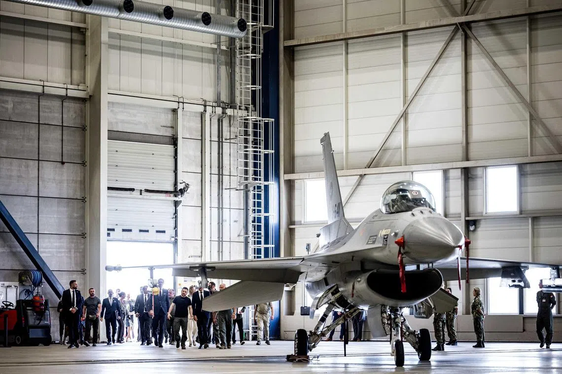Ukrainian President Volodymyr Zelensky (centre) visits an air base in the Netherlands to have a look at an F-16 fighter jet.