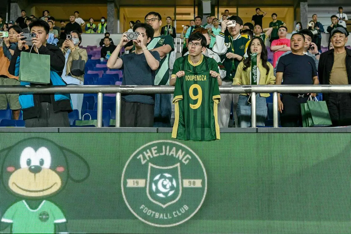 A fan holds a T-shirt with the name and number of Gabon international striker Aaron Boupendza during the Chinese Super League match between Zhejiang FC and Meizhou Hakka in Hangzhou.