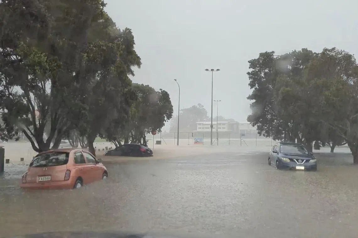 Cars are seen in a flooded street during heavy rainfall in Auckland, on Jan 27, 2023