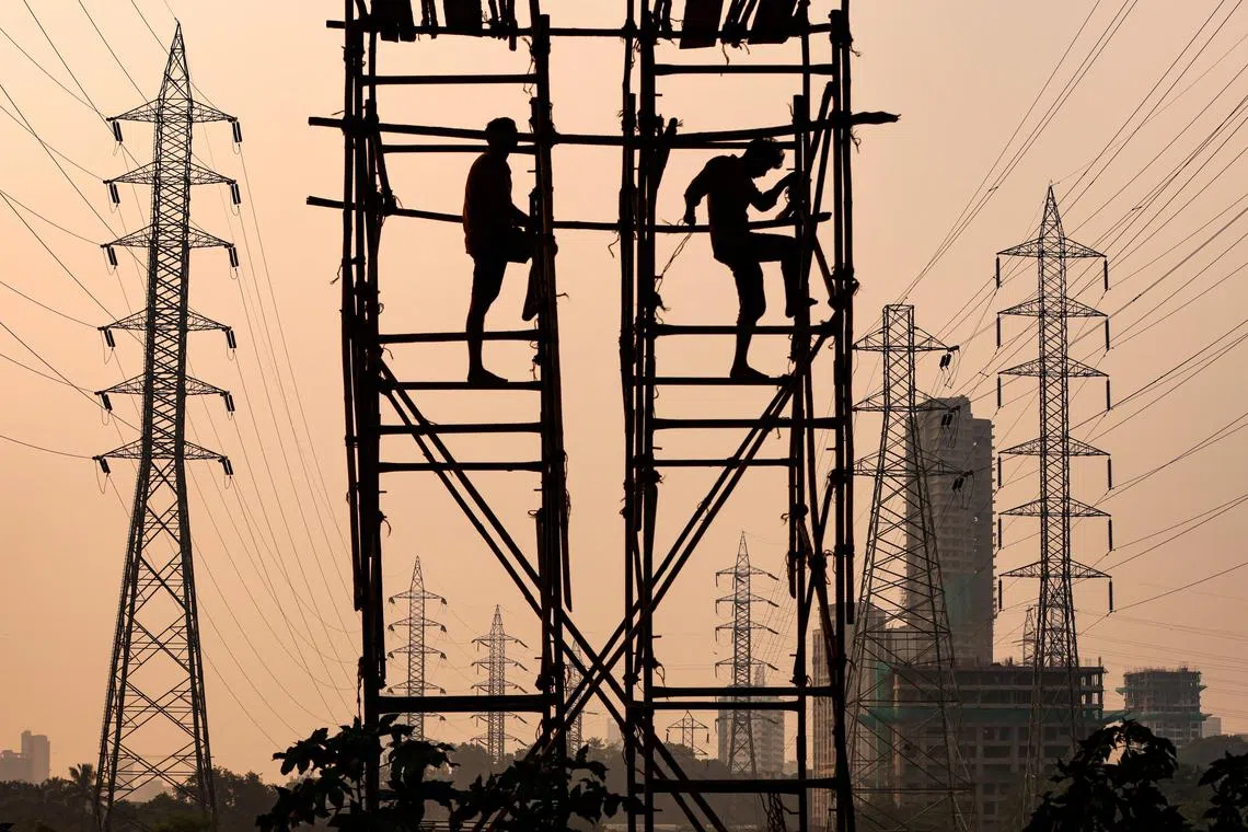 FILE PHOTO: Labourers work next to electricity pylons in Mumbai, India, October 13, 2021. REUTERS/Francis Mascarenhas/File Photo