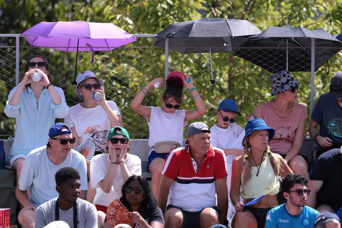 Paris 2024 Olympics - Tennis - Men's Singles Second Round - Roland-Garros Stadium, Paris, France - July 30, 2024. Spectators use umbrellas to protect themselves from the sun during the match between Lorenzo Musetti of Italy and Mariano Navone of Argentina. REUTERS/Claudia Greco