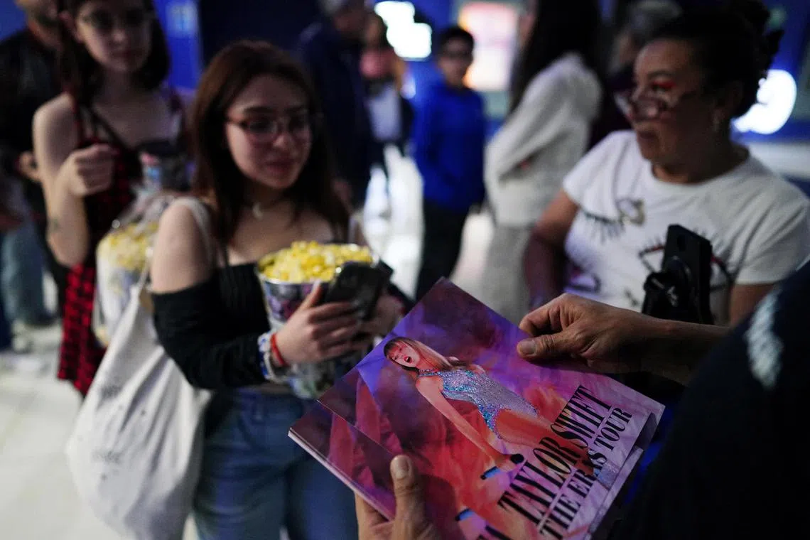 Fans receive a photograph of Taylor Swift as they enter a cinema to watch Taylor Swift: The Eras Tour in Mexico.