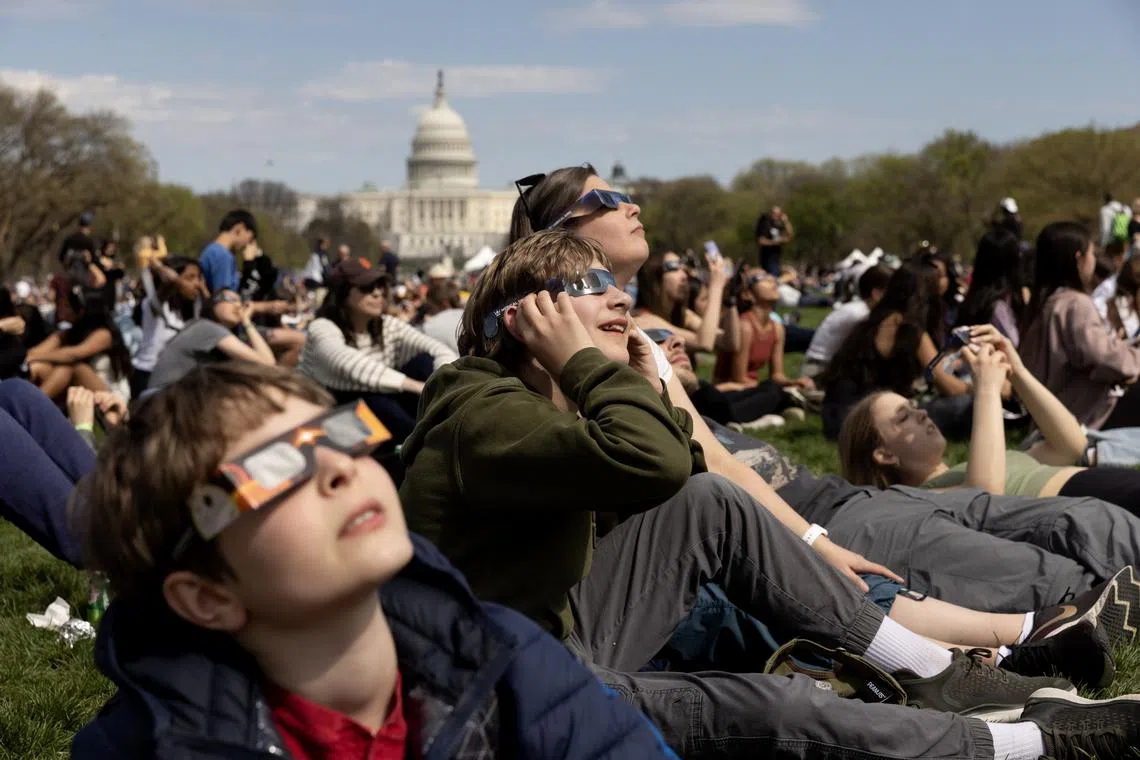 People on the National Mall looking at the solar eclipse in Washington, DC, on April 8, 2024. 