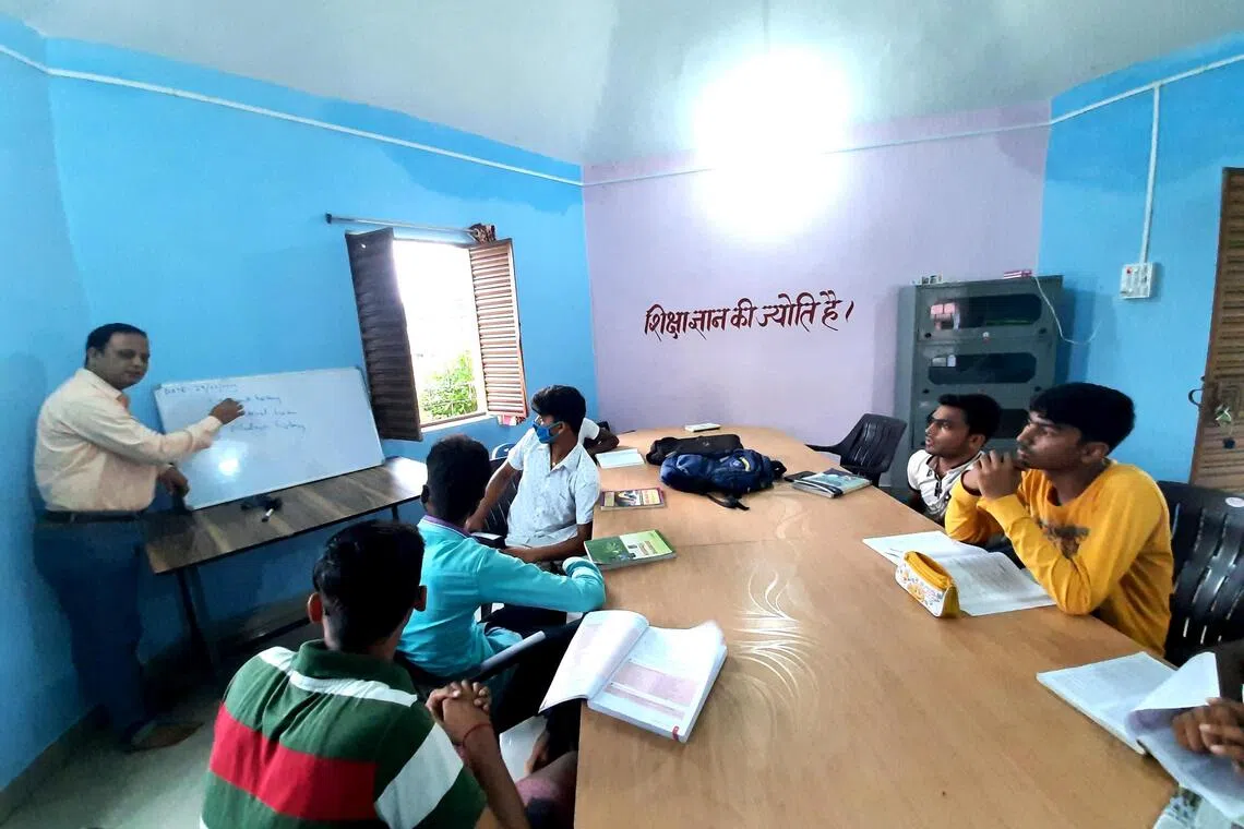 A local government official helping students to prepare for competitive exams for government jobs, at the community library in Charghara village in Jamtara.