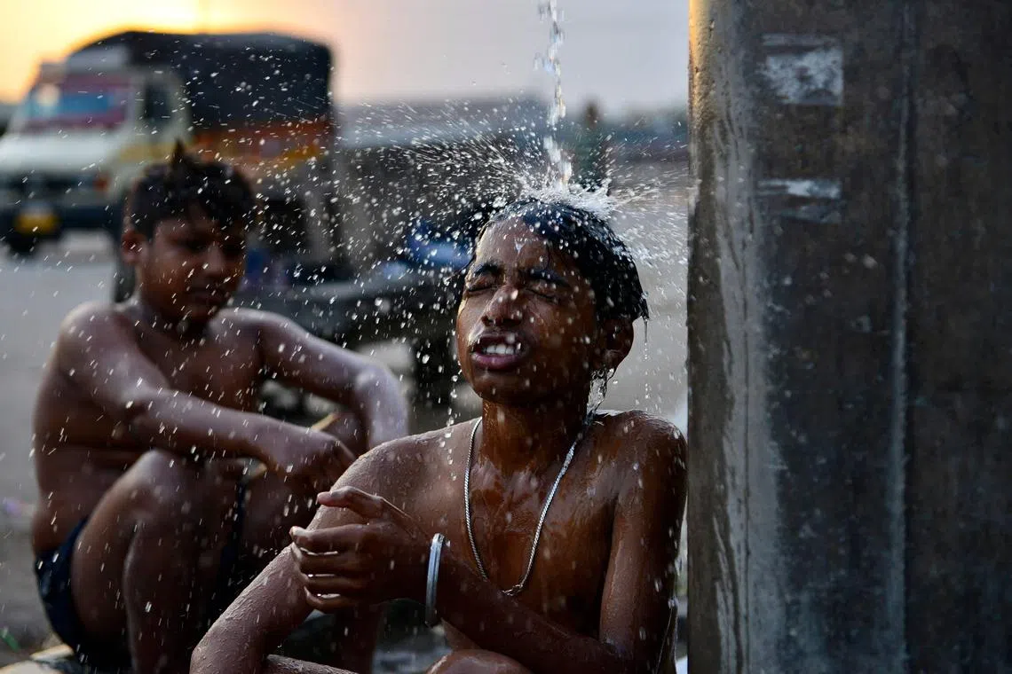 Boys bathe at a public water facility along a street on a hot summer day in Jalandhar on June 13, 2024 amid heatwave. India's heatwave is the longest ever to hit the country, the government's top weather expert said on June 10 as he warned people will face increasingly oppressive temperatures. Parts of northern India have been gripped by a heatwave since mid-May, with temperatures soaring over 45 degrees Celsius (113 degrees Fahrenheit). (Photo by Shammi MEHRA / AFP)