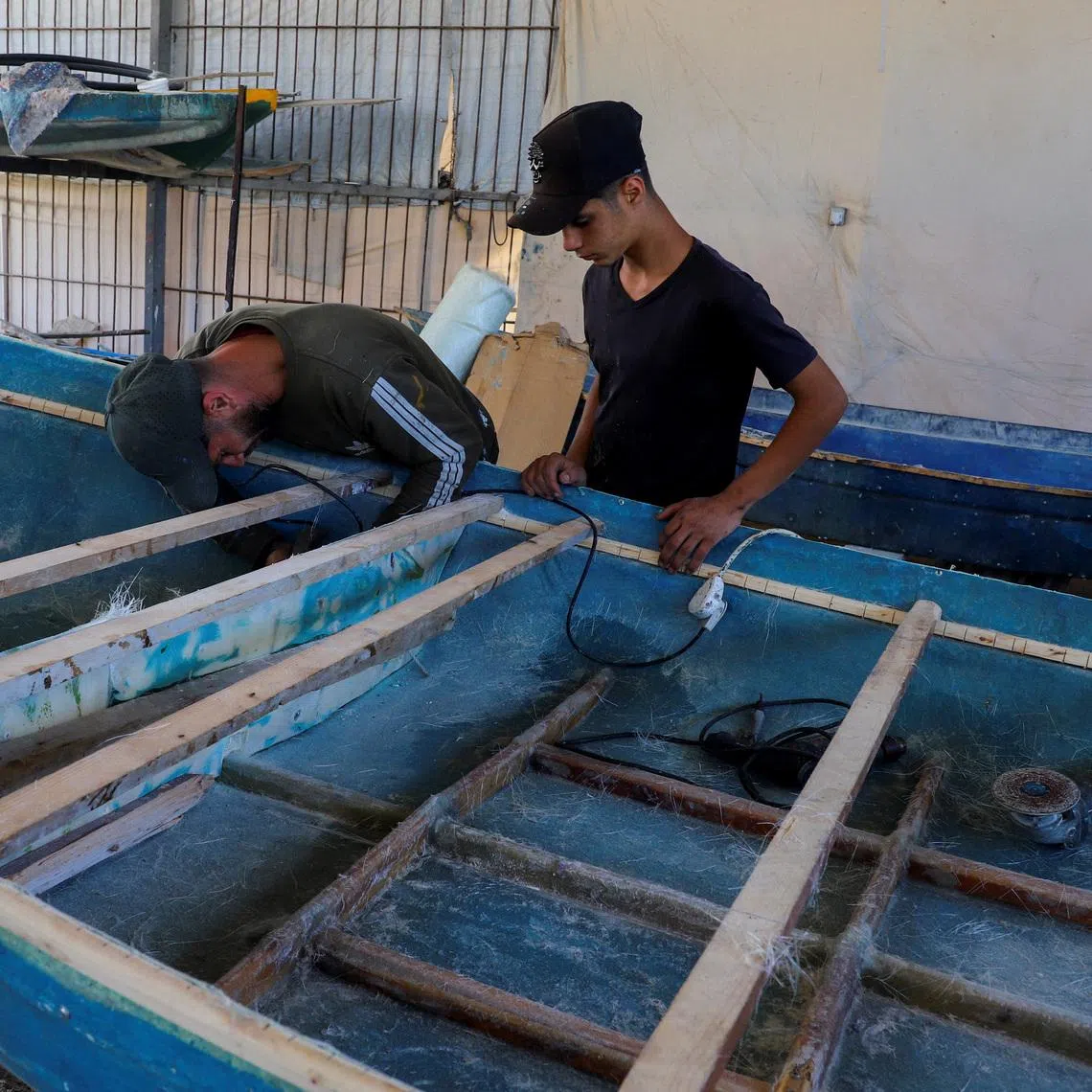Palestinian workers repairing a skiff damaged in the Israeli offensive, in Gaza City on June 3.