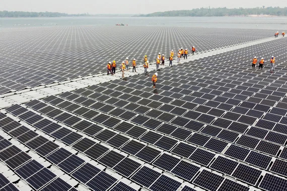 FILE PHOTO: Workers walk between solar cell panels over the water surface of Sirindhorn Dam in Ubon Ratchathani, Thailand April 8, 2021. Picture taken April 8, 2021 with a drone. REUTERS/Prapan Chankaew/File Photo