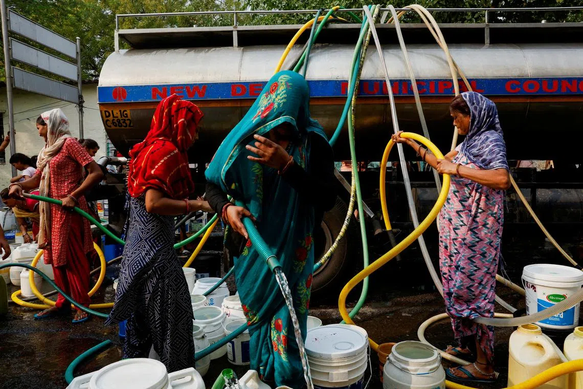 Residents use pipes to fill their containers with drinking water from a water tanker during a hot day in New Delhi, India, June 24, 2024. REUTERS/Priyanshu Singh