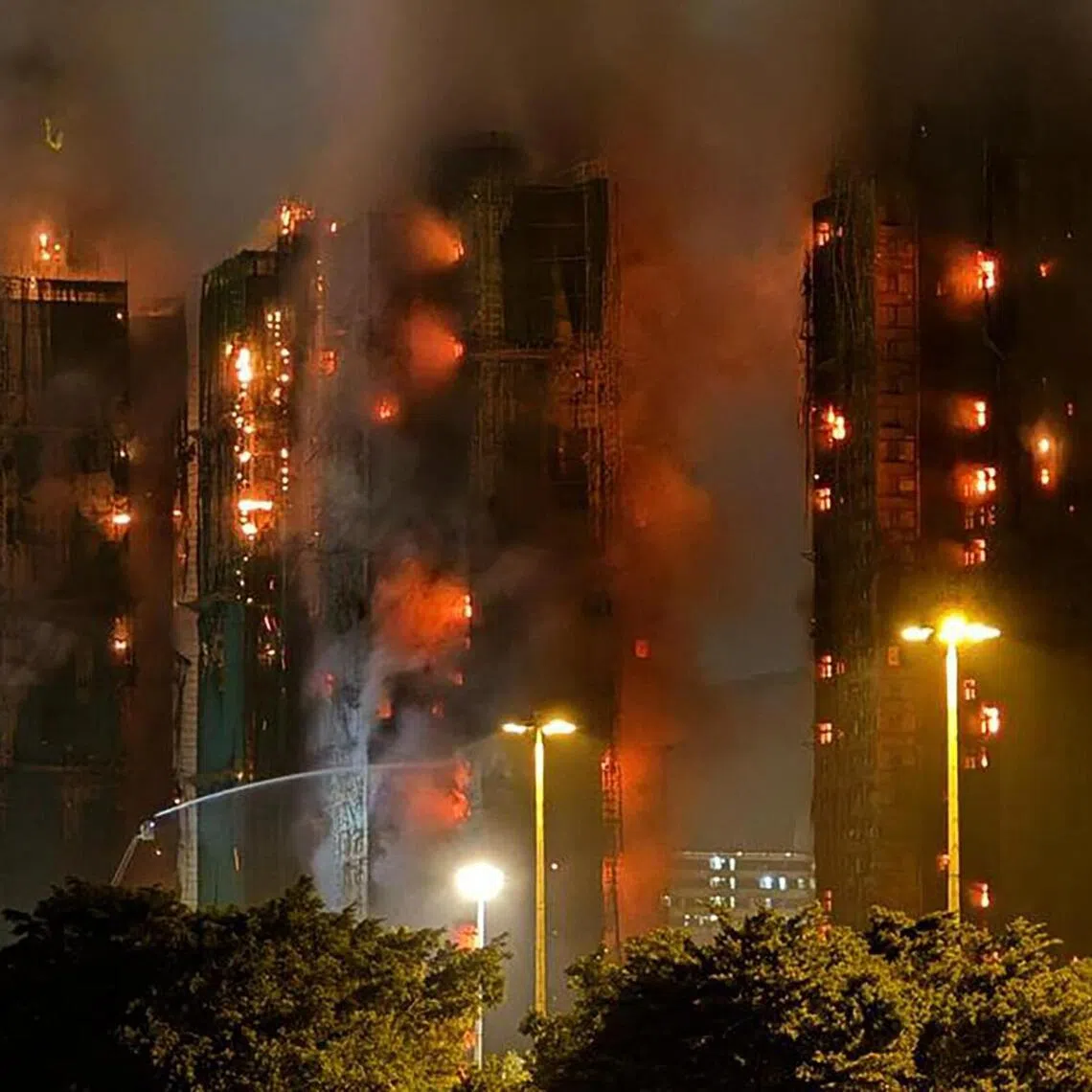 (FILES) Thick smoke and flames rise as a major fire engulfs several apartment blocks at the Wang Fuk Court residential estate in Hong Kong's Tai Po district on November 26, 2025. An independent committee investigating a devastating fire that ripped through a Hong Kong housing complex last year began a series of public hearings on march 19, 2026, into the blaze that killed 168 people. (Photo by Yan ZHAO / AFP)