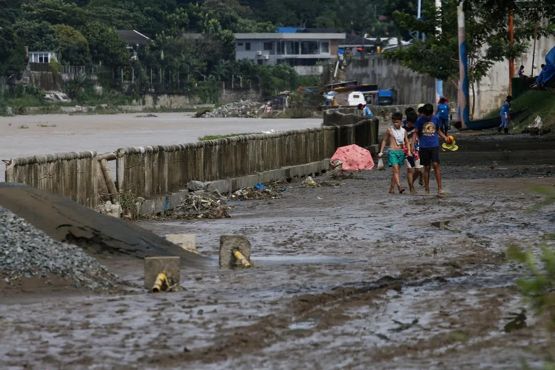 Children walk along a muddied path after Typhoon Nalgae flooded a riverside park in Marikina City, in the Philippines Oct 30, 2022. 
